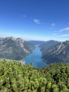 Aussicht über den ganzen Achensee: Klare Sicht auf See und Berge, grüne Wälder und steile Hänge prägen das Panorama.