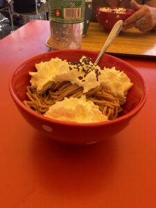 Dessertpause auf der Lombachalp – Maroni-Dessert mit Schlagrahm in roter Schale auf sonniger Terrasse.