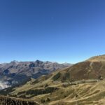 Weite Berglandschaft mit Blick Richtung Simmental – sanfte Hänge, klare Herbstfarben und wolkenloser Himmel über den Berner Alpen.