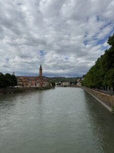 Blick über den Fluss Adige in Verona mit der Skyline der Altstadt und bewölktem Himmel.