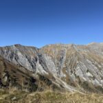 Steile, graue Felsflanken unter blauem Himmel – eindrucksvolle Kontraste am Blumenweg oberhalb des Hahnenmoospasses.