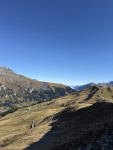 Blick auf den Hahnenmoospass mit geschwungenem Weg – klare Herbststimmung und weite Sicht bis ins Simmental.