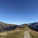Kiesweg auf dem Höhenrücken Richtung Hahnenmoospass – Panoramaweg mit Ausblick über das Engstligental.