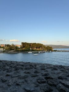 Yachthafen mit Segelbooten und kleiner bewaldeter Halbinsel im goldenen Abendlicht auf Krk.