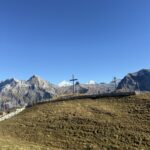 Kreuz und Wanderweg mit Alpenpanorama – herbstliche Berglandschaft am Hahnenmoospass bei klarer Fernsicht.