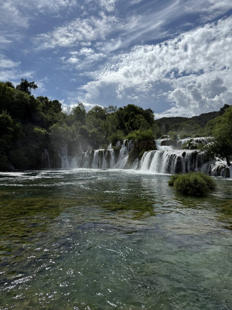 Die berühmten Skradinski Buk Wasserfälle im Krka-Nationalpark mit klarer Wasseroberfläche und bewölktem Himmel.