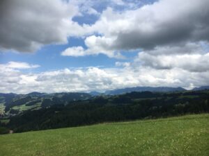 Panoramablick über die sanften Hügel des Emmentals mit wechselndem Wolkenspiel und weiter Sicht.