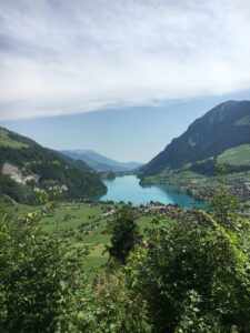 Lungernsee von oben: Weitblick über den türkisblauen Lungernsee im Tal, eingerahmt von Bergen und Wiesen.