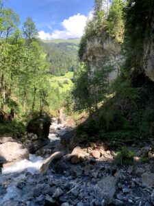 Blick in die Cholerenschlucht Adelboden mit felsigen Ufern, Bachlauf und grüner Berglandschaft.