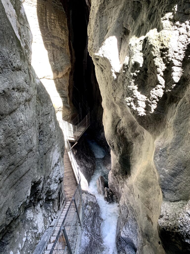 Schmaler Steg mit Geländer zwischen den hohen Felsen der Cholerenschlucht in Adelboden.