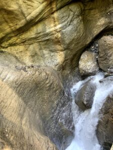Wasserfall in glattgeschliffener Felsschlucht mit einfallendem Sonnenlicht.