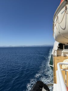 Aussicht vom Deck einer Fähre auf das weite, tiefblaue Meer vor der kroatischen Küste, mit Rettungsboot und Sonnenschein.