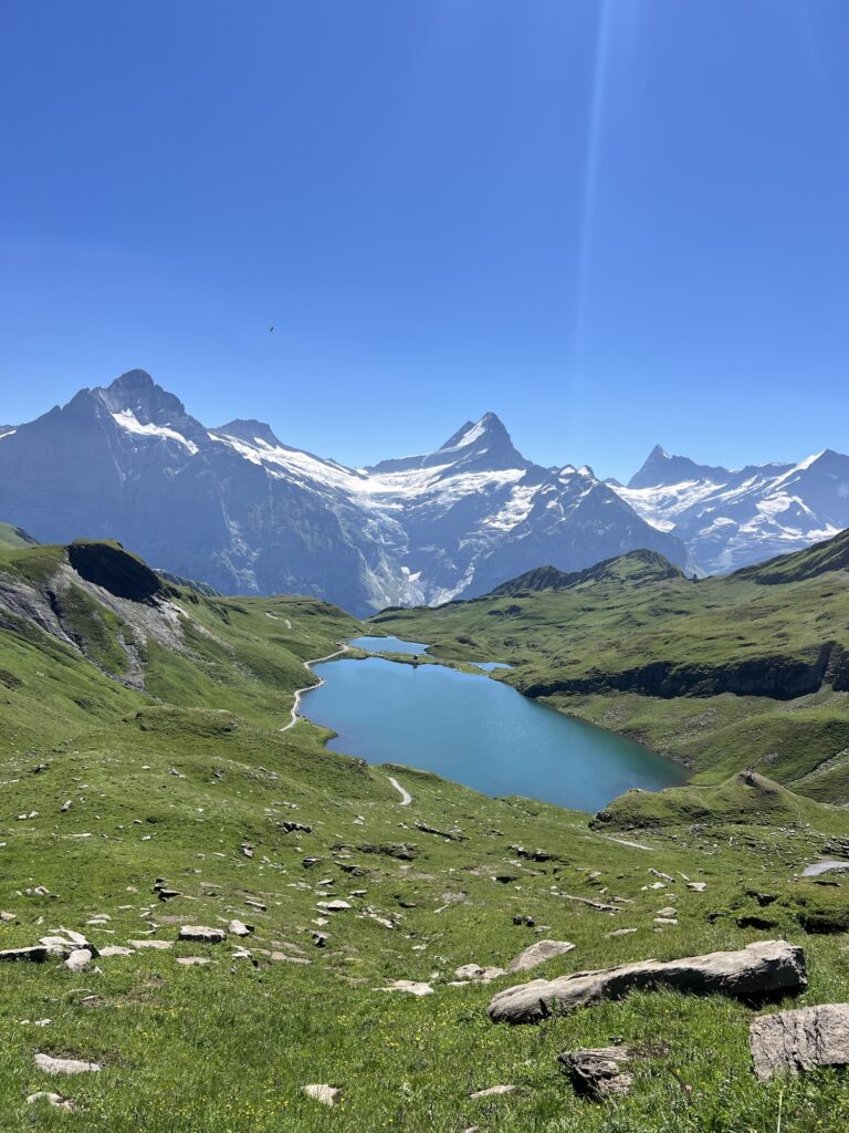 Blick auf türkisblauen Bachsee (Bachalpsee) mit schneebedeckten Gipfeln im Hintergrund auf der First–Axalp-Route.