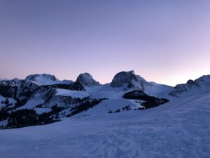 Violetter Winterhimmel beim Sonnenuntergang auf dem Gurnigel; verschneite Gipfel rund um den Selibühl und das Gantrischgebiet in sanftem Abendlicht.