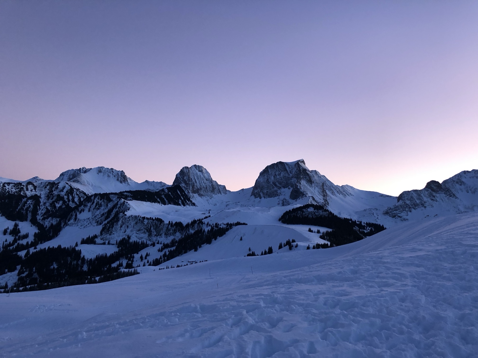 Violetter Winterhimmel beim Sonnenuntergang auf dem Gurnigel; verschneite Gipfel rund um den Selibühl und das Gantrischgebiet in sanftem Abendlicht.