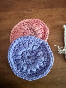 Gehäkelte Abschminkpads aus Baumwolle in Rosa und Lila auf Holztisch