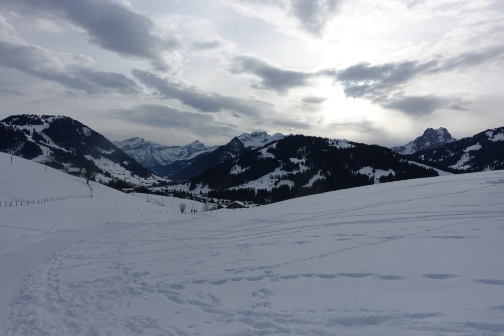Winterliche Panoramaaussicht über das Saanenland mit verschneiten Hügeln und Bergketten nahe Gstaad