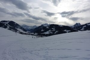 Winterliche Panoramaaussicht über das Saanenland mit verschneiten Hügeln und Bergketten nahe Gstaad