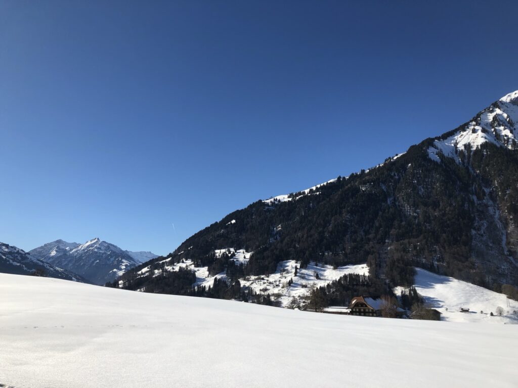 Verschneite Landschaft beim Winterwandern in Aeschiried mit weitem Panorama und blauem Himmel