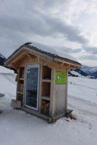 Selbstbedienungshütte am Winterwanderweg bei Saanenmöser mit Blick auf verschneite Wiesen und Berglandschaft im Saanenland