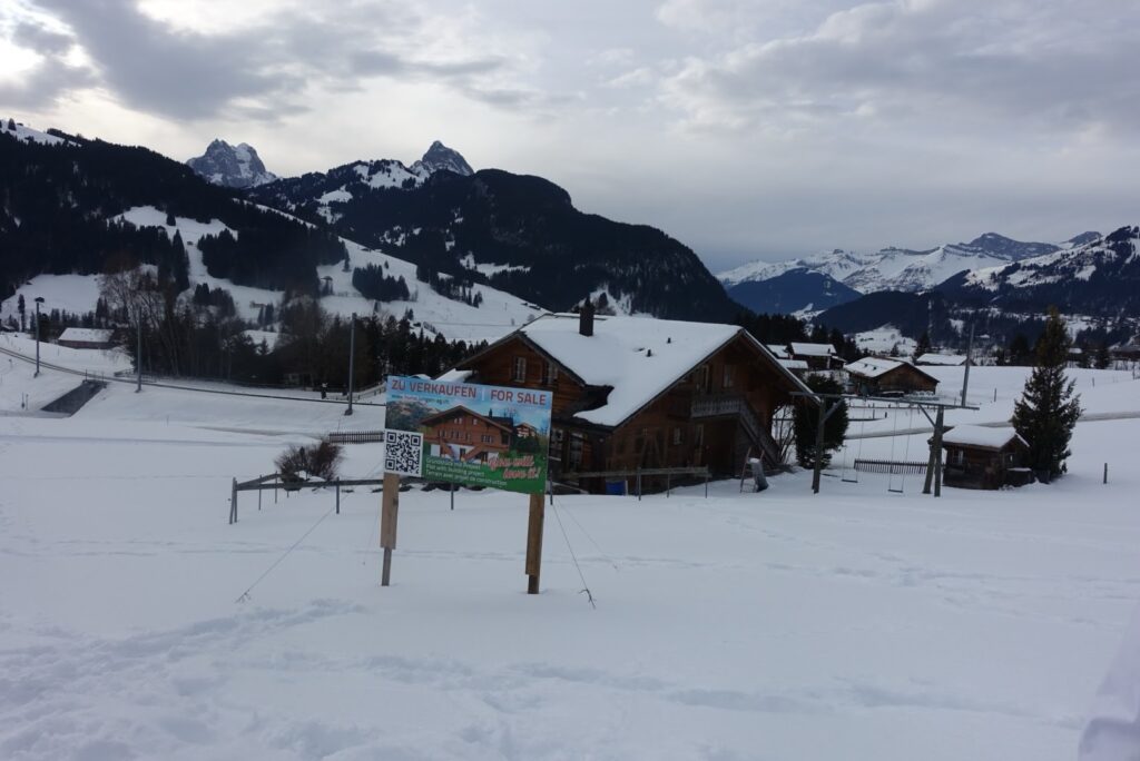 Typisches Chalet im Saanenland entlang des Winterwanderwegs zwischen Schönried und Gstaad, umgeben von Schnee und Bergen