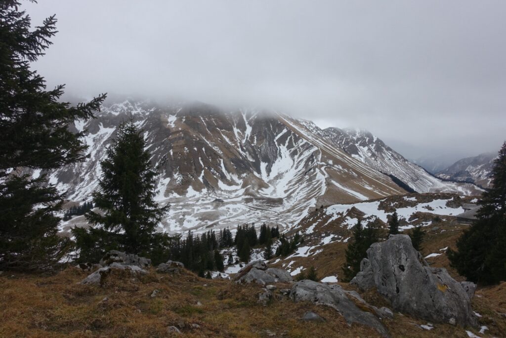 Aussicht auf die Freiburger Voralpen bei der Winterwanderung Schwarzsee – Hohberg mit Nebel und schroffen Berghängen