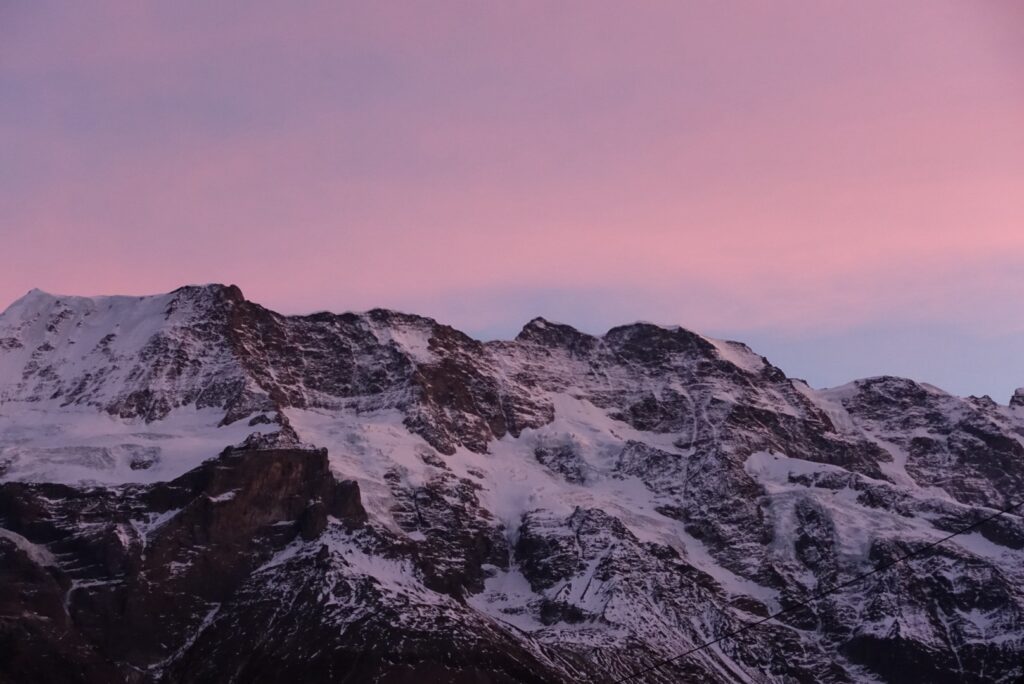 Winterliches Bergpanorama mit rosafarbenem Himmel über den verschneiten Berner Alpen bei Sonnenuntergang
