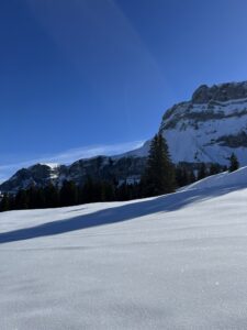 Sanft abfallende Winterlandschaft auf der Axalp mit Felswänden und tiefem Schnee