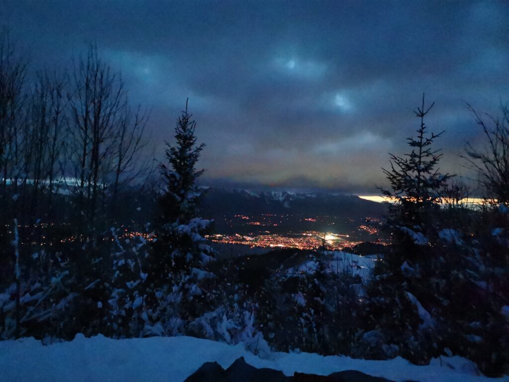 Abendstimmung über dem Tal bei Heiligenschwendi mit Lichtern im Hintergrund – Winterwanderung Blueme