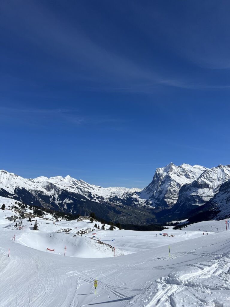 Panoramablick über verschneite Hänge und Berge beim Winterwandern nahe der Kleinen Scheidegg im Berner Oberland.