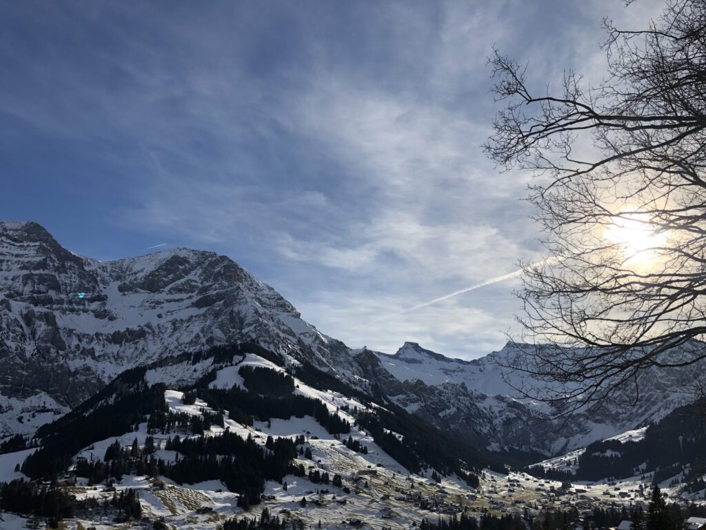 Winterlandschaft bei Adelboden mit Bergpanorama, Sonne und leicht bewölktem Himmel