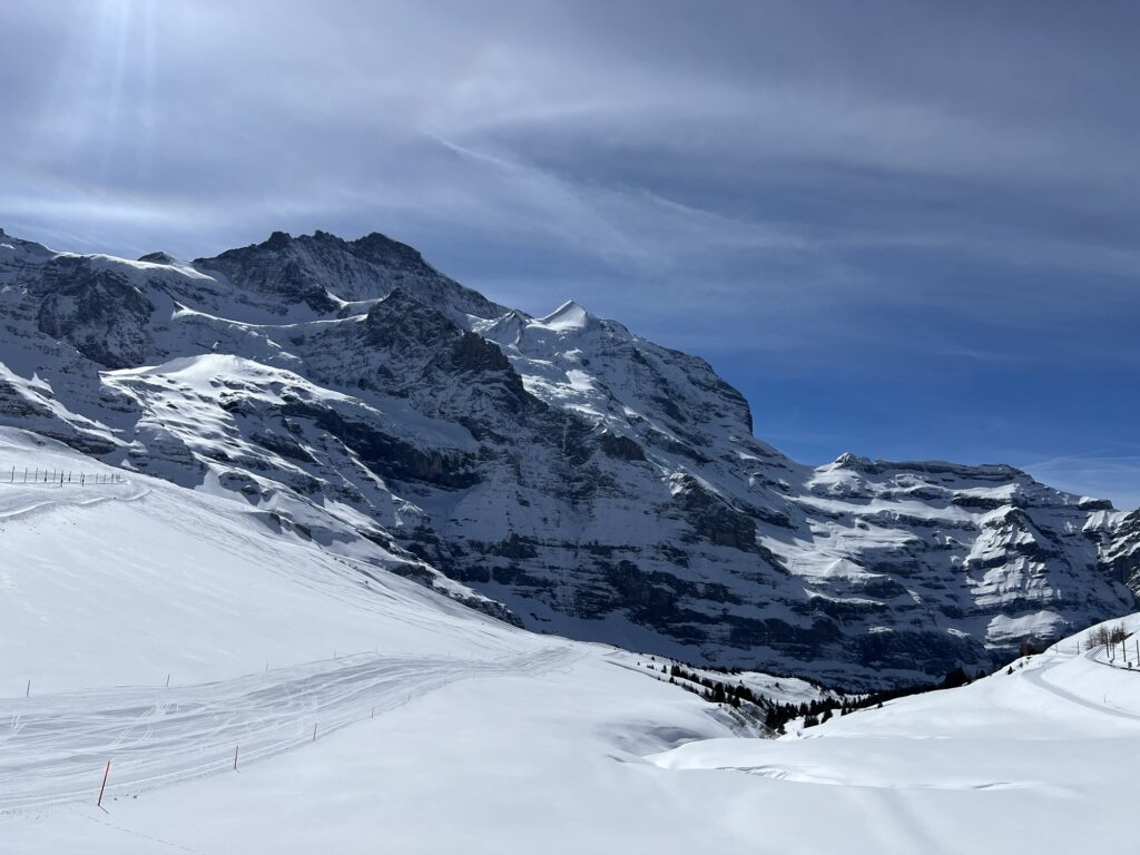 Sanft geschwungene Schneefelder und imposante Felswände entlang der Winterwanderung im Berner Oberland.