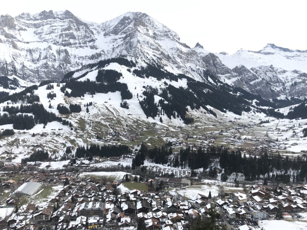 Blick über Adelboden im Winter mit Dorfkern, schneebedeckten Dächern und umliegender Bergkulisse