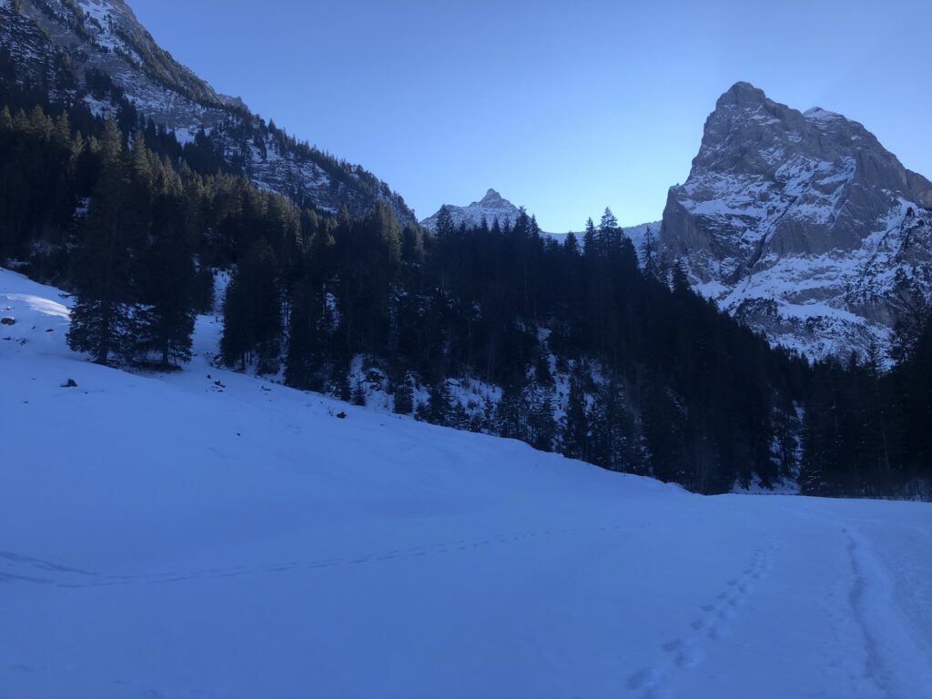 Verschneite Talebene mit Blick auf markante Felsformationen bei Rosenlaui im Winter