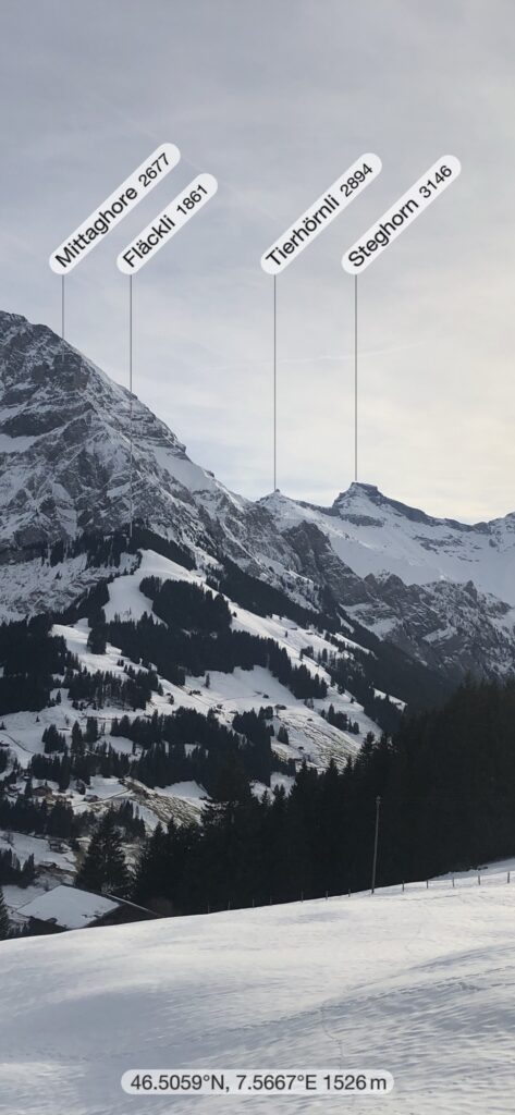 Panoramablick vom Hörelirundweg über Adelboden mit beschrifteten Berggipfeln im Winter