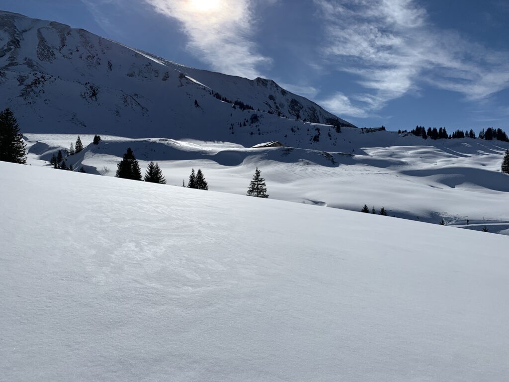 Verschneite Hänge der Lombachalp mit Blick auf umliegende Berge im Winter