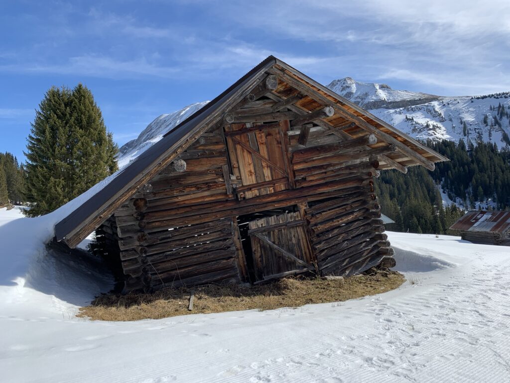 Alphütte auf der Lombachalp im Winter mit verschneiter Umgebung