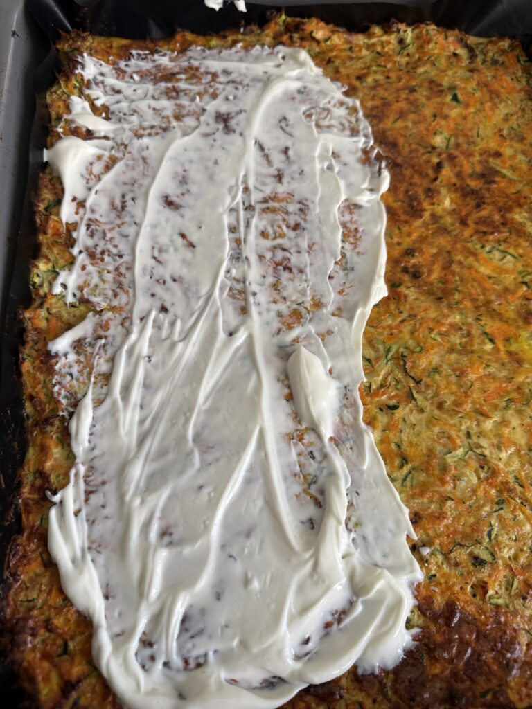 Zucchini-Karotten-Boden frisch aus dem Ofen, bestrichen mit cremigem Frischkäse als Basis für einen gesunden Gemüse-Wrap