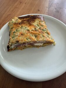 Goldbraun gebackener Zucchini-Karotten-Boden auf Backpapier, knuspriger Rand und saftige Mitte, perfekte Grundlage für Low-Carb-Rezepte