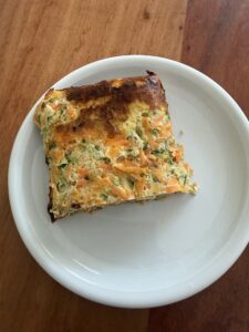 Gebackenes Stück Zucchini-Karotten-Boden auf weissem Teller, goldbraun und saftig, ideal als gesunder Snack oder leichte Mahlzeit