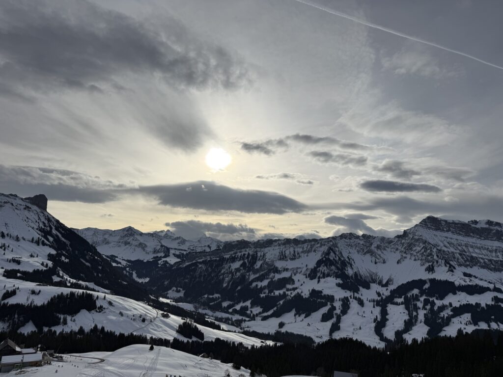 Sonnenlicht über verschneiten Bergen bei der Winterwanderung auf der Marbachegg im Entlebuch