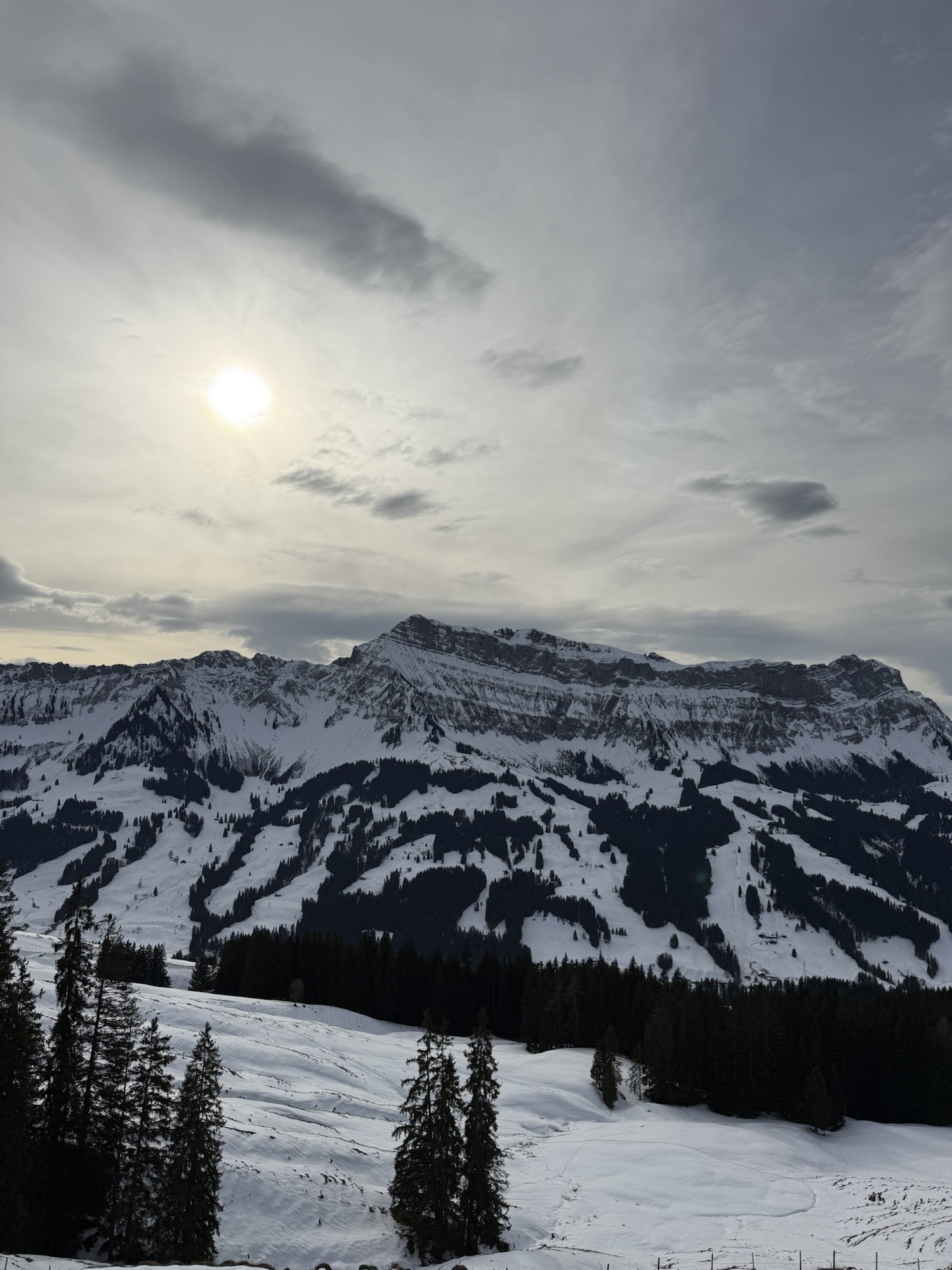 Sonnenlicht über verschneiten Bergen bei der Winterwanderung auf der Marbachegg im Entlebuch