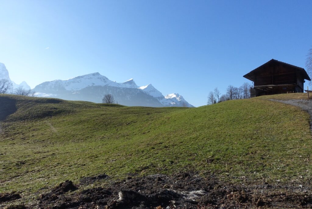 Historisches Holzhaus am Hasliberg mit Blick auf die verschneiten Berge entlang des Panoramawegs im Winter