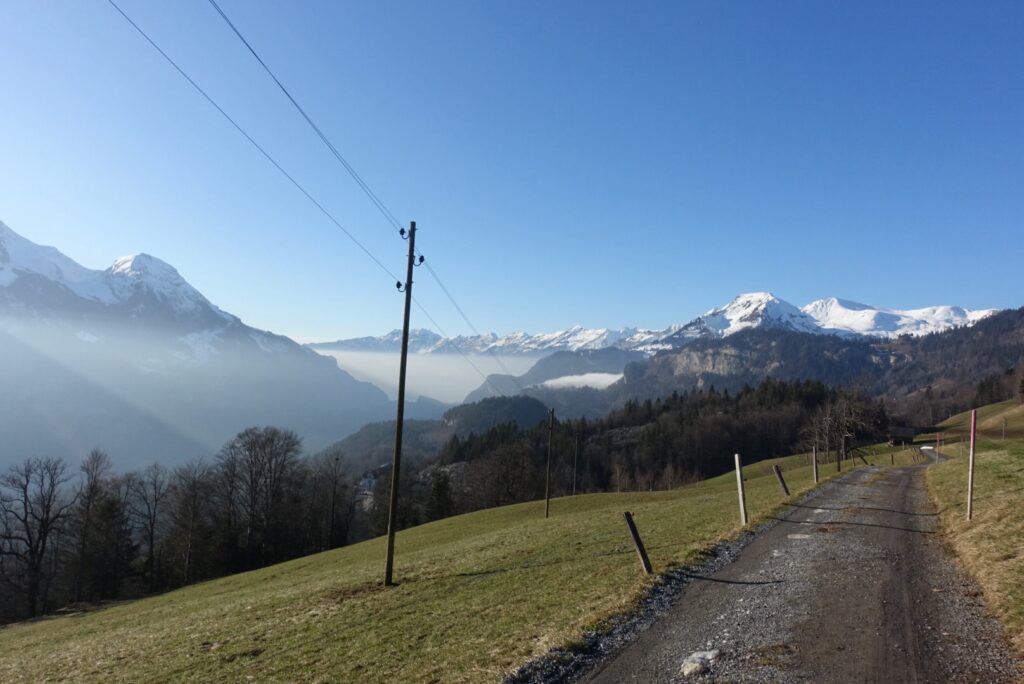 Winterwanderweg am Panoramaweg Hasliberg mit Blick ins Haslital und schneebedeckte Berge bei sonnigem Wetter