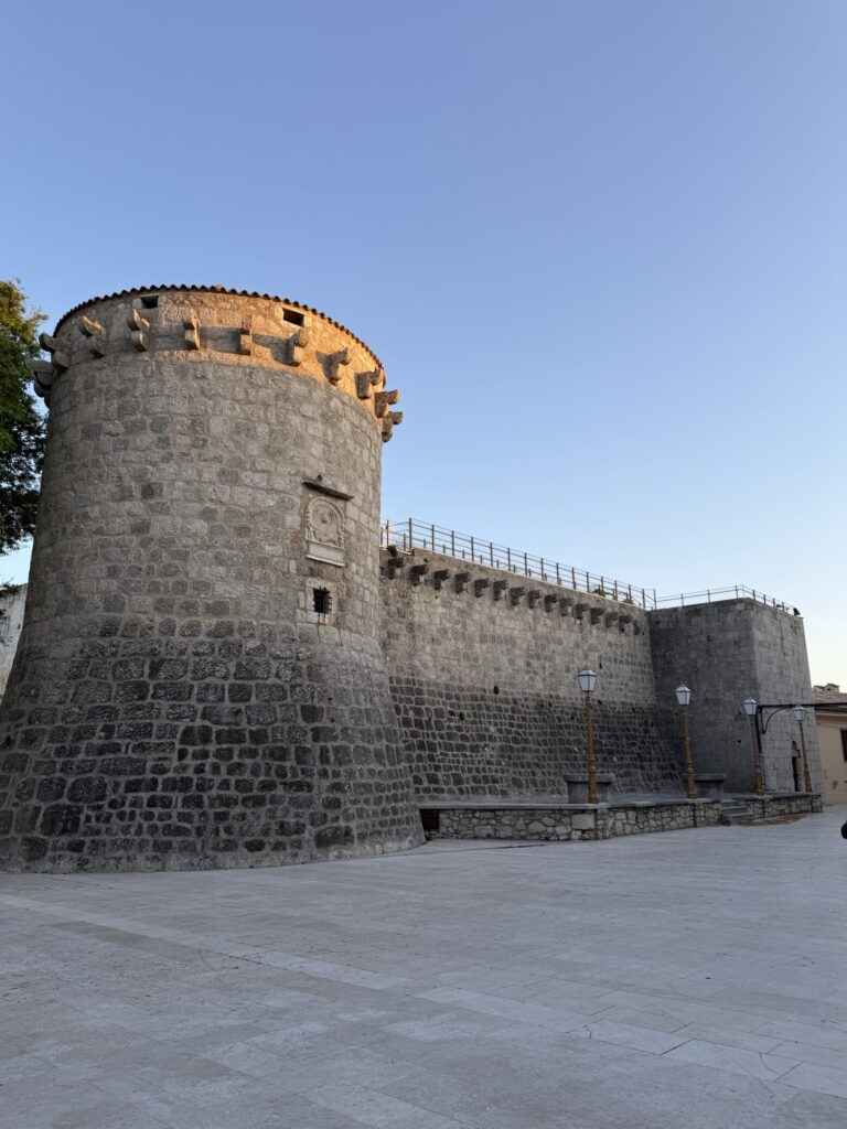Historische Stadtmauer von Krk-Stadt aus hellem Naturstein bei Abendlicht unter klarem Himmel.