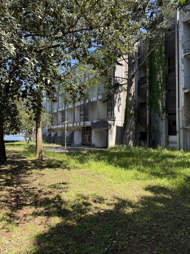 Weiterer Blick auf den verlassenen Lost Place auf Krk mit zerfallener Fassade, Graffiti und Natur, die sich das Gebäude zurückholt.