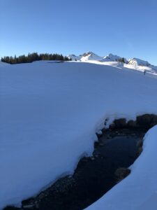 Kleiner Bach unter Schneedecke auf der Elsigen-Metsch während einer Winterwanderung