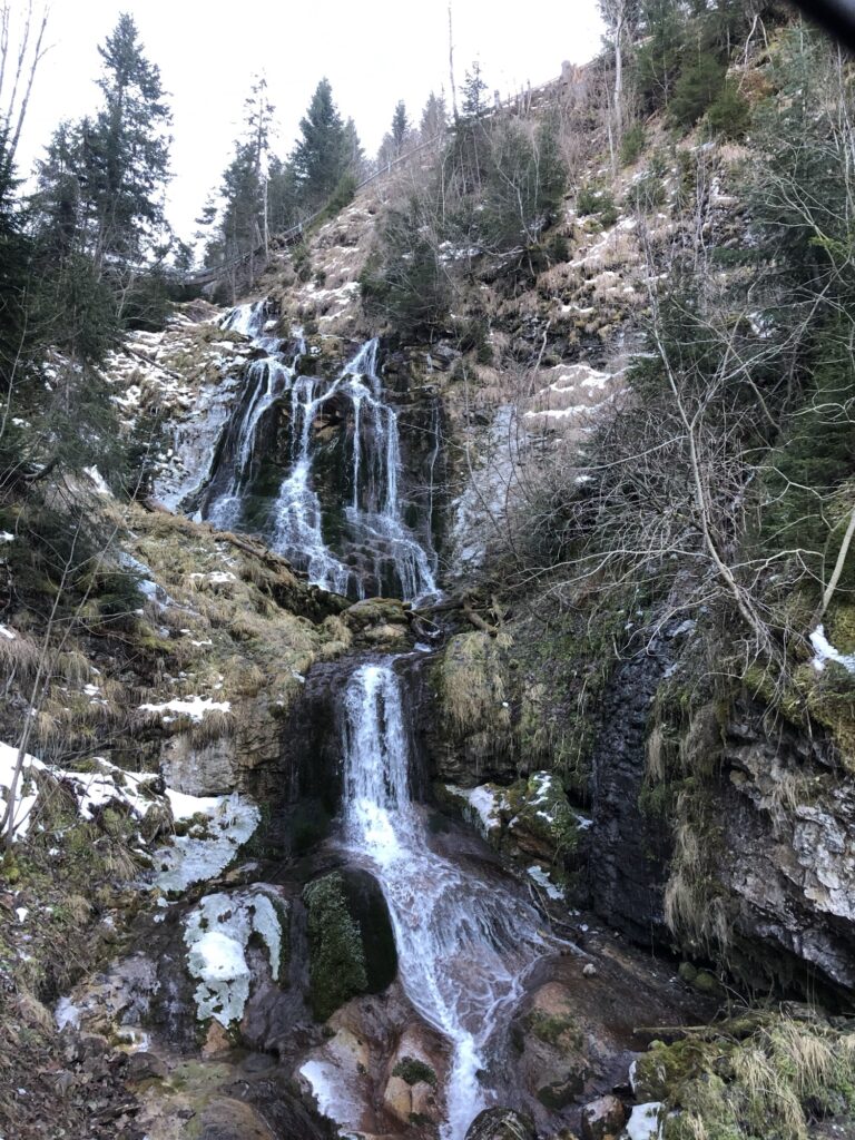 Wasserfall nahe Elsigen-Metsch im Winter mit Felsen, Moos und Schneeresten