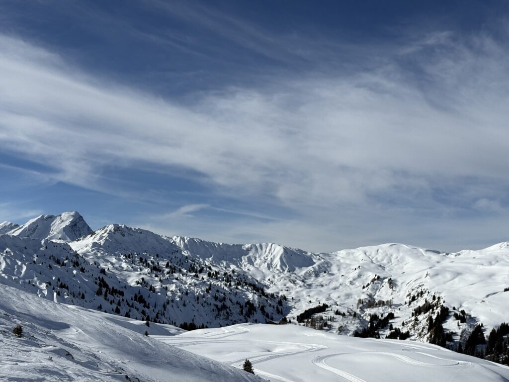 Panoramablick bei der Winterwanderung am Betelberg oberhalb der Lenk im Berner Oberland mit verschneiten Gipfeln und weitem Winterhimmel.