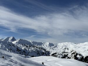 Panoramablick bei der Winterwanderung am Betelberg oberhalb der Lenk im Berner Oberland mit verschneiten Gipfeln und weitem Winterhimmel.